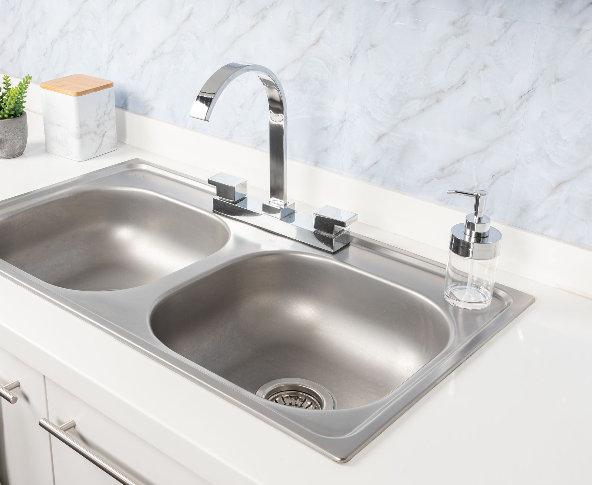 A kitchen sink with two sinks and a soap dispenser.