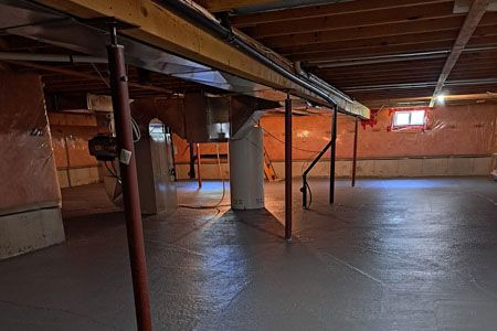 Empty basement with exposed beams, support posts, and concrete floor under low ceiling.