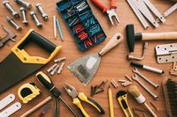Assorted hand tools and fasteners spread on a wooden workbench
