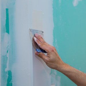 Hand sanding blue wall paint with a small scraper tool