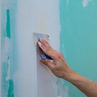Hand sanding blue wall paint with a small scraper tool