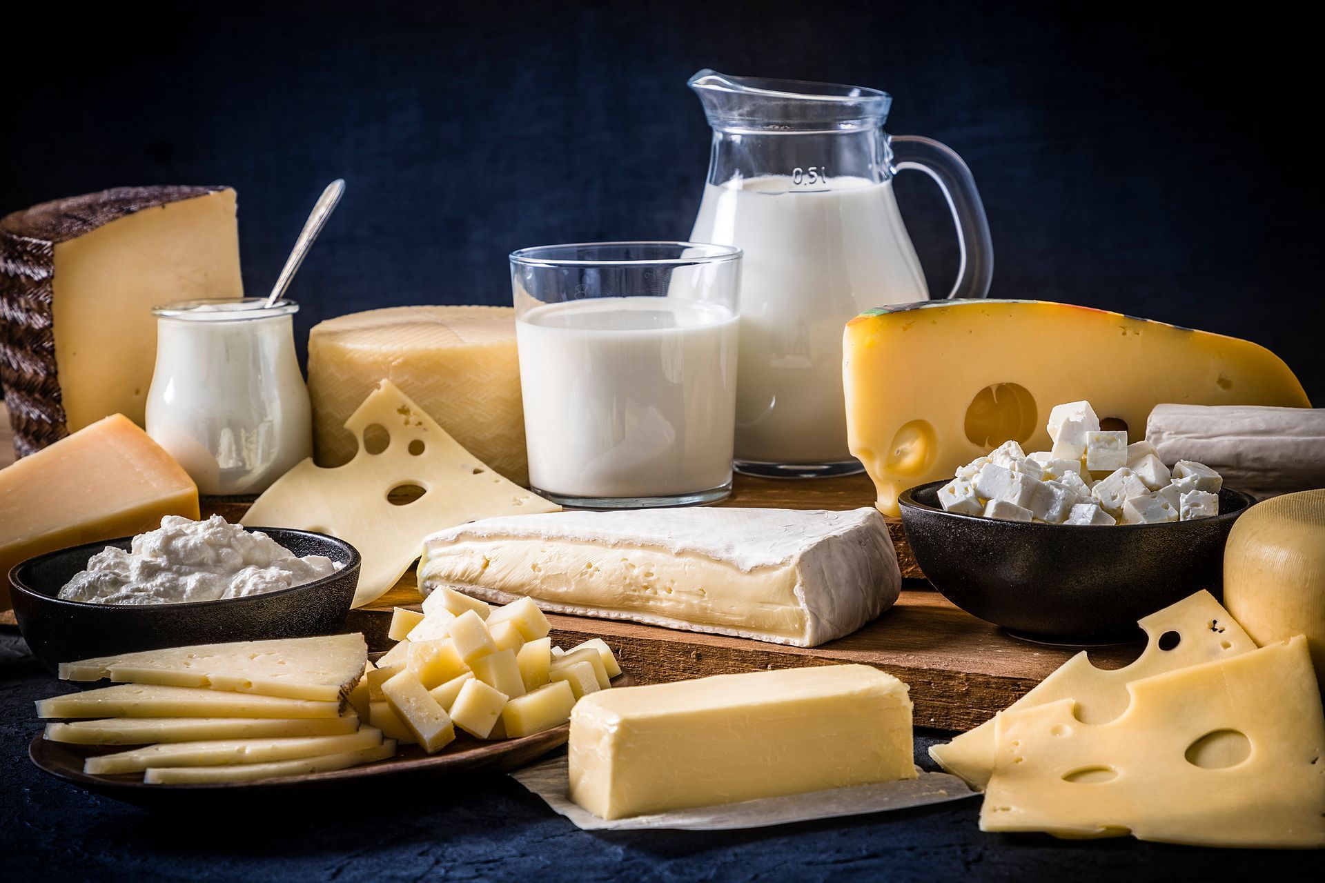 There are many different types of cheese and milk on the table.