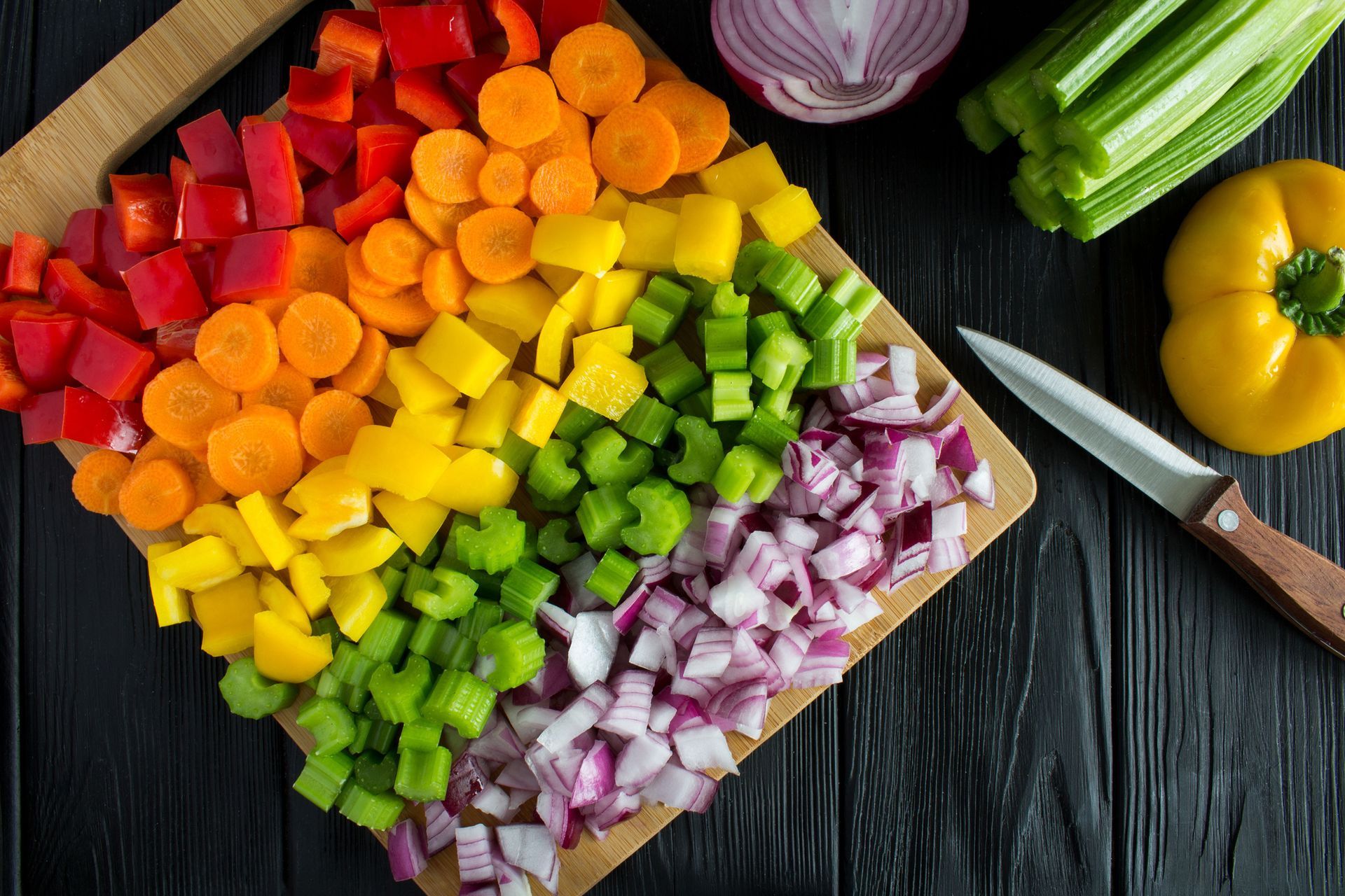 A cutting board filled with chopped vegetables in the shape of a rainbow.