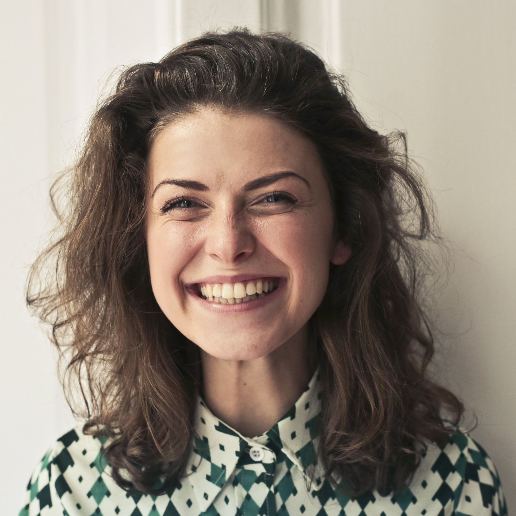 A woman wearing a green and white checkered shirt is smiling