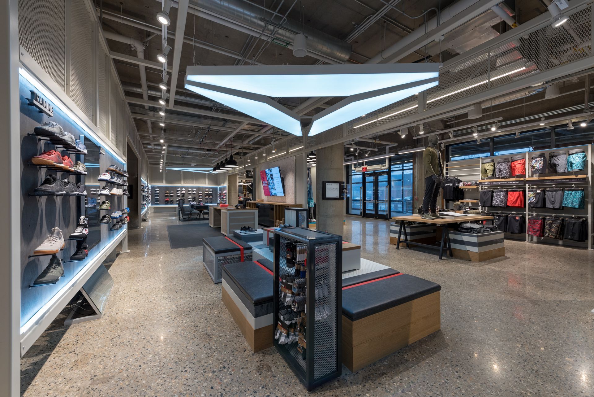 A large under armour store with a lot of shoes on display.