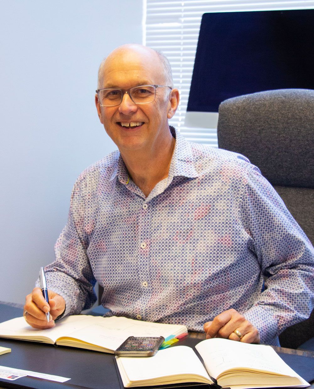A man is sitting at a desk writing in a notebook