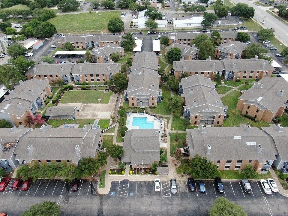 An aerial view of a large apartment complex with a pool