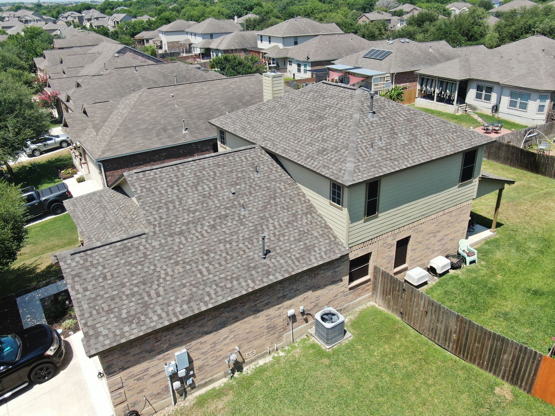 An aerial view of a house with a new roof in a residential area.
