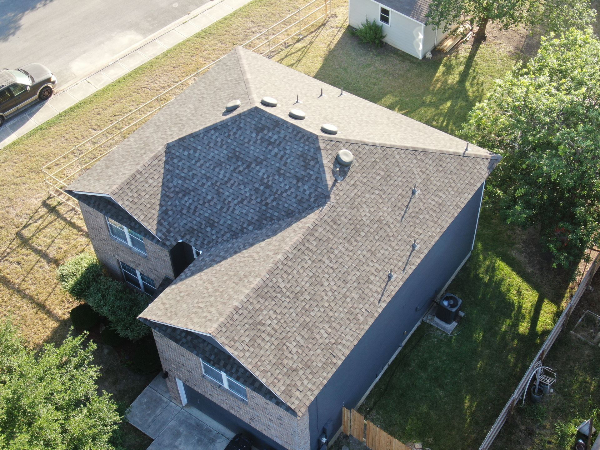 An aerial view of a house with a roof and a car parked in front of it.