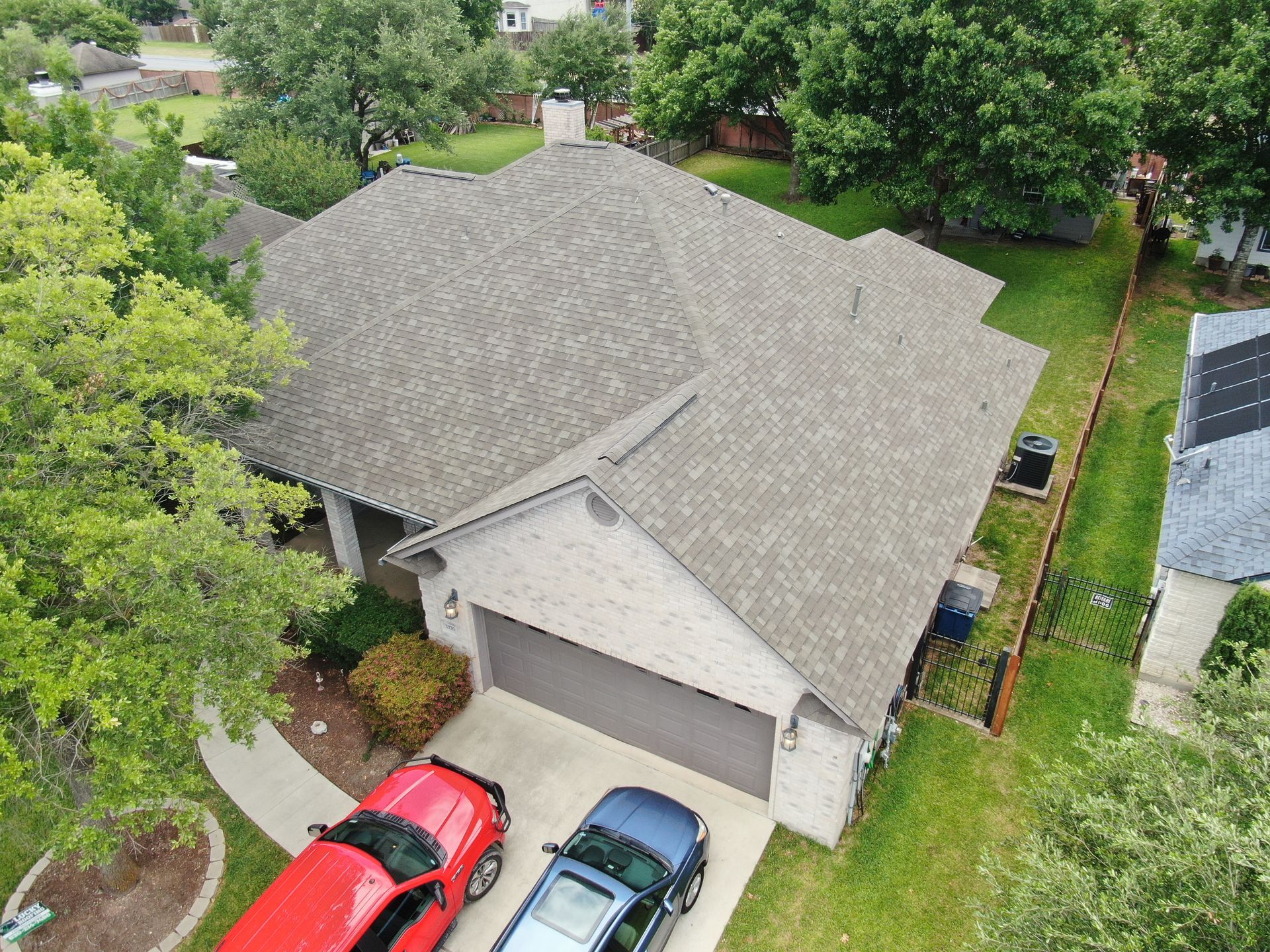 An aerial view of a house with two cars parked in front of it.