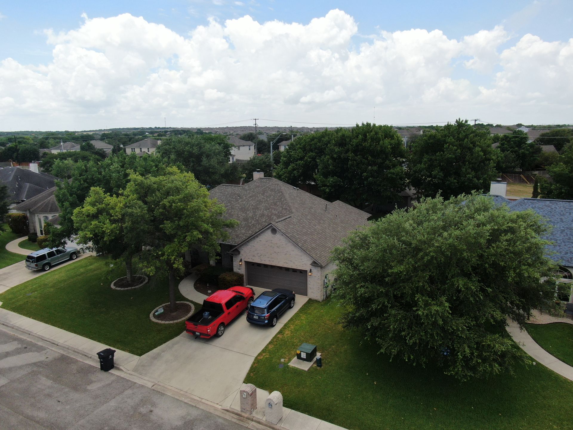 An aerial view of a house with two cars parked in the driveway.