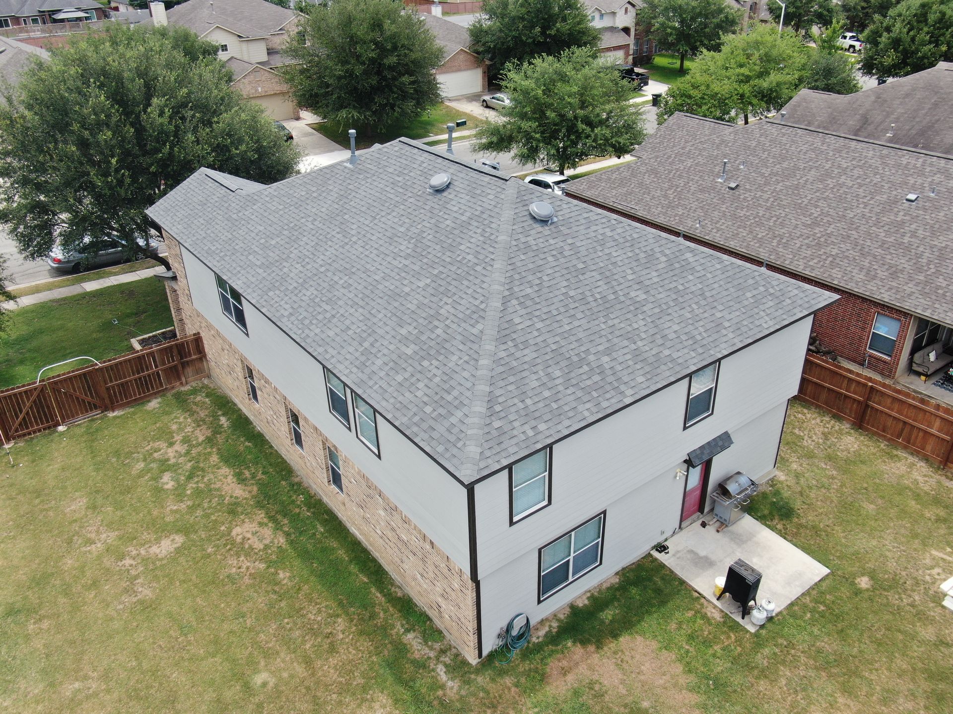An aerial view of a house with a gray roof in a residential area.