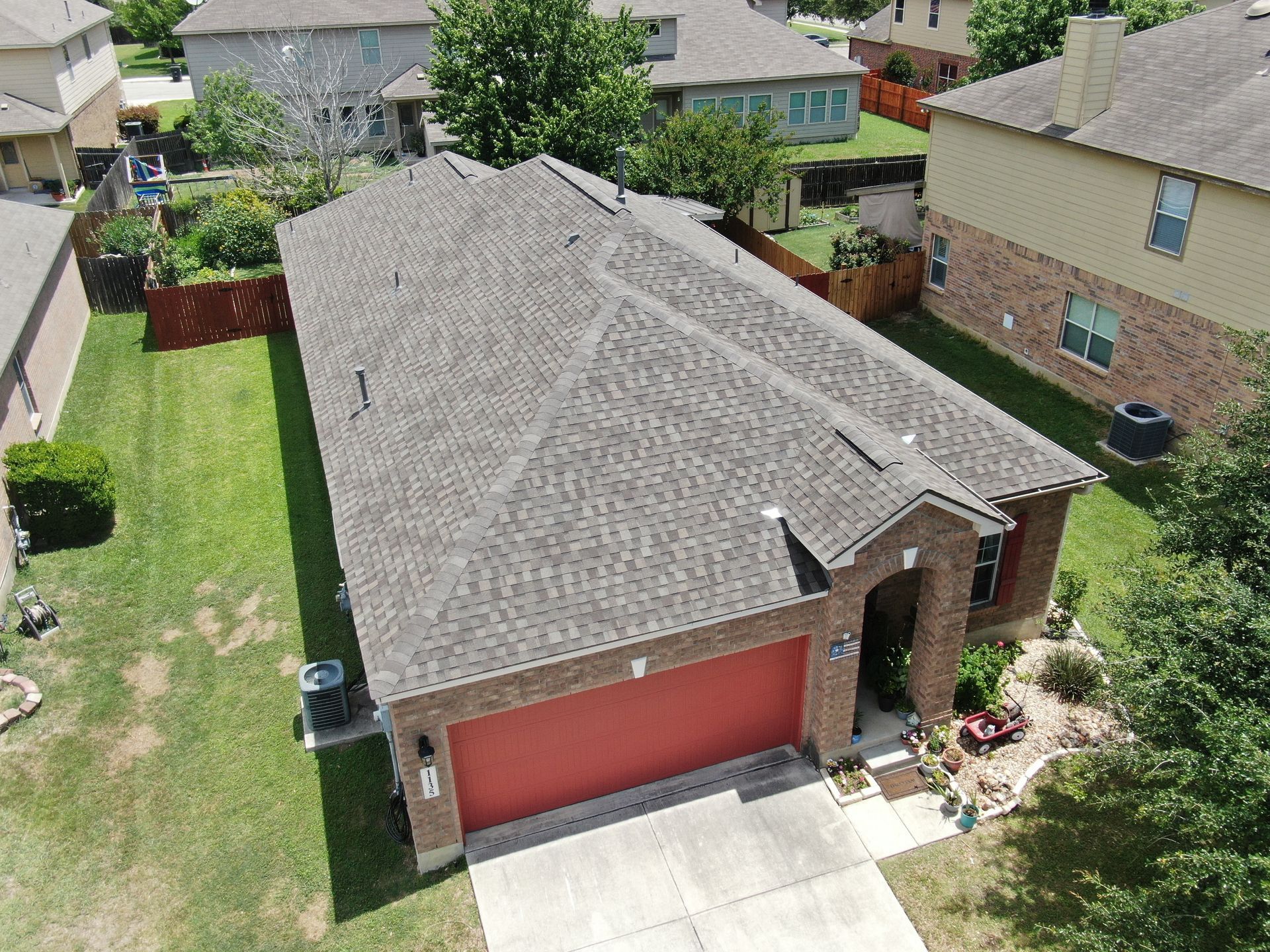 An aerial view of a house with a gray roof and a red garage door.