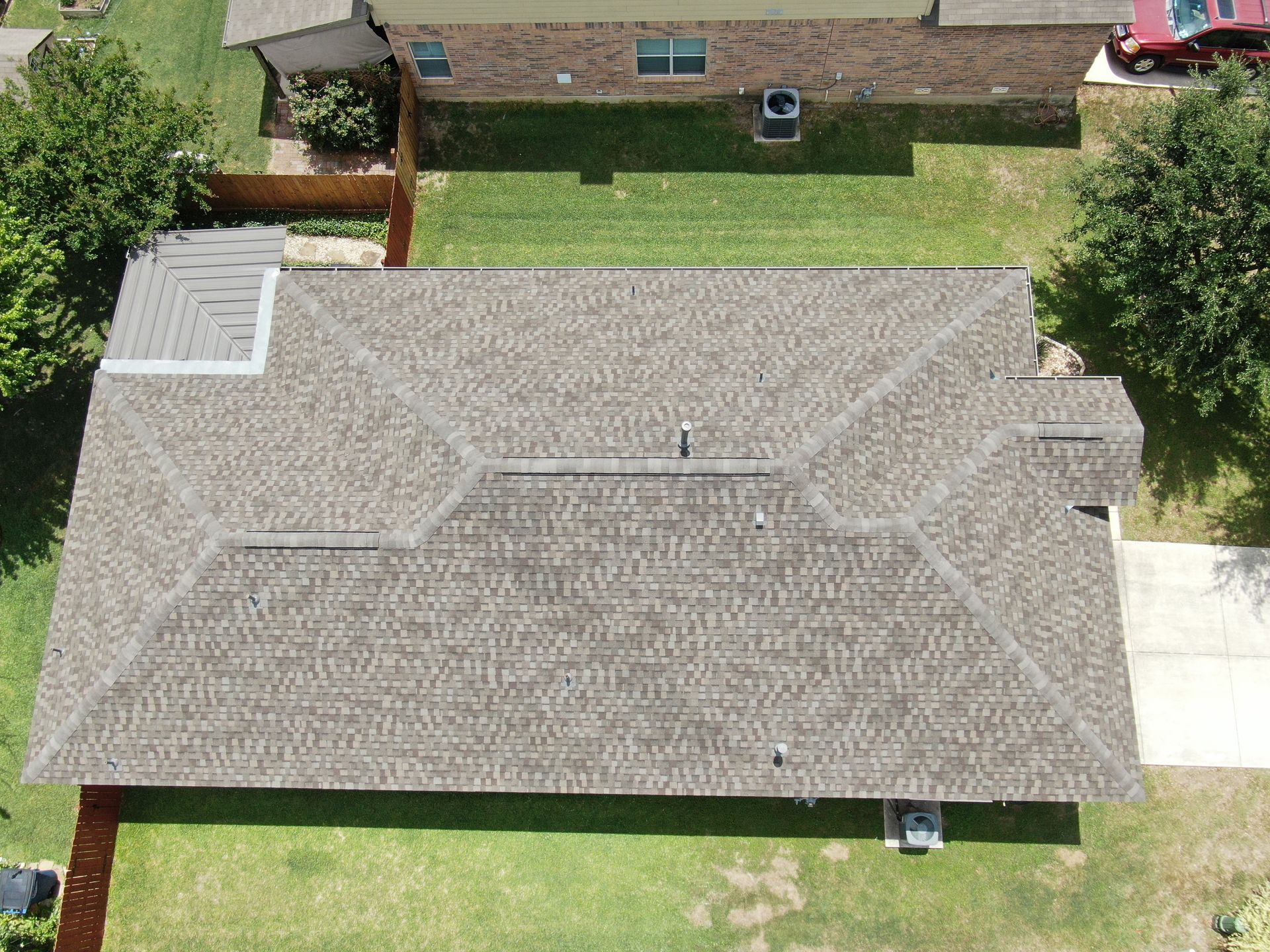An aerial view of a house with a roof and a driveway.