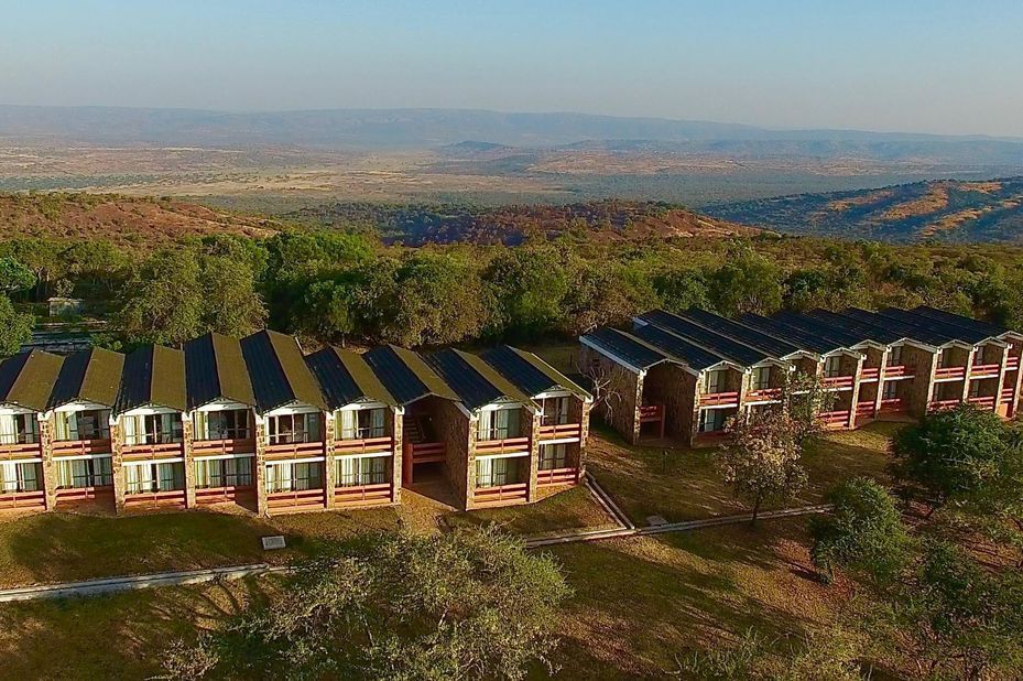 Safari tourists on vehicle roof observing rhinos under sunny sky, Akagera