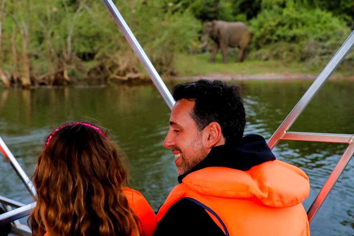Tourists on a boat in lake Ihema looking at elephants taking a dip