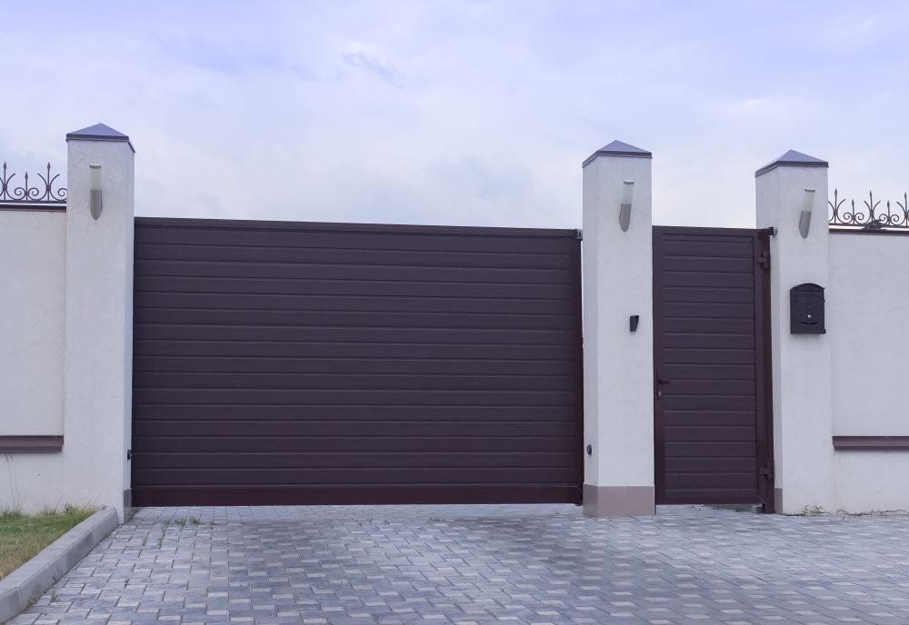 A Brown Sliding Gate is Sitting Next to a White Fence — Airlie Beach Garage Doors In Cannonvale, QLD