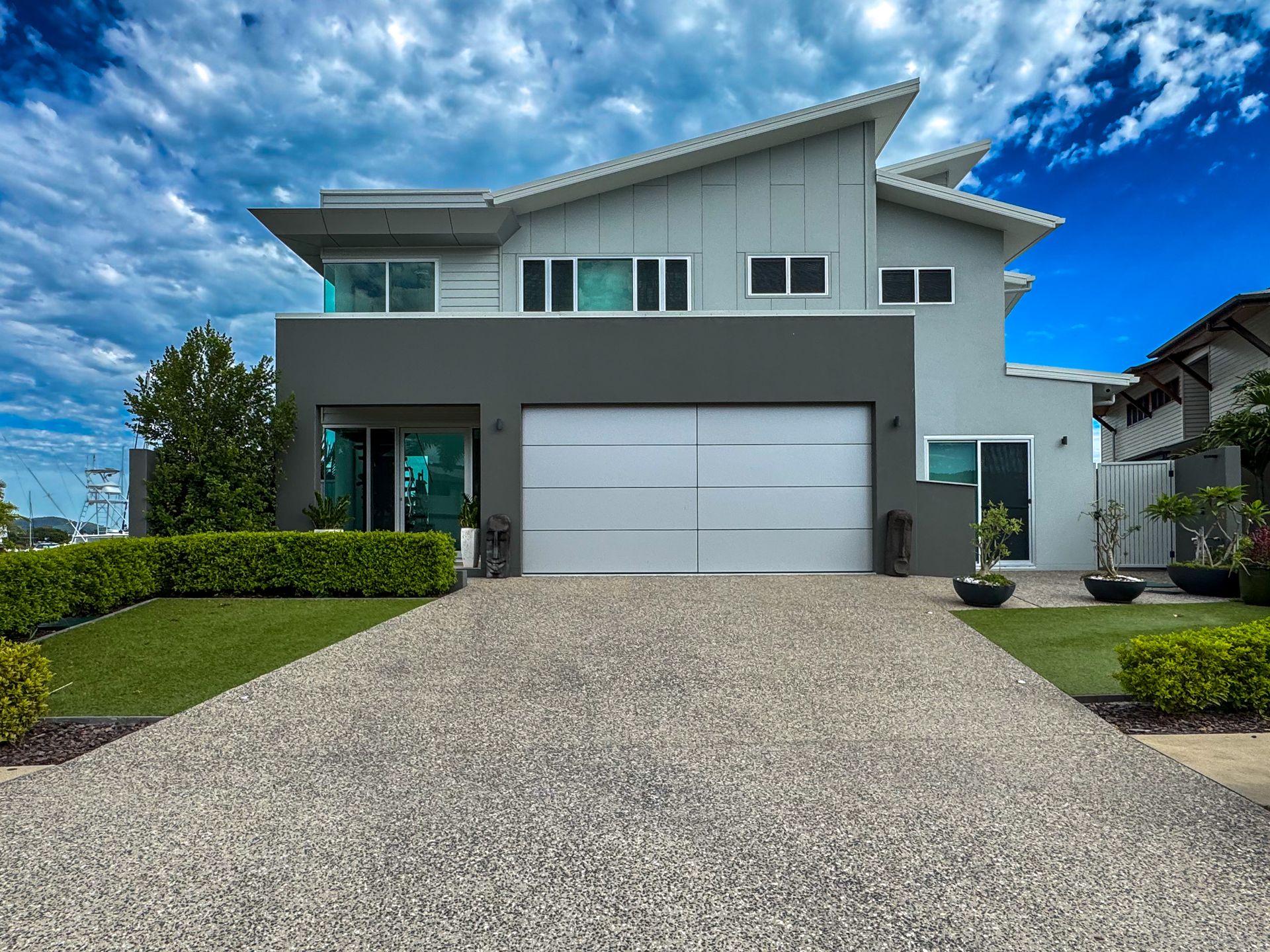 A Black Garage Door is Sitting on the Side of a White Building — Airlie Beach Garage Doors In Cannonvale, QLD