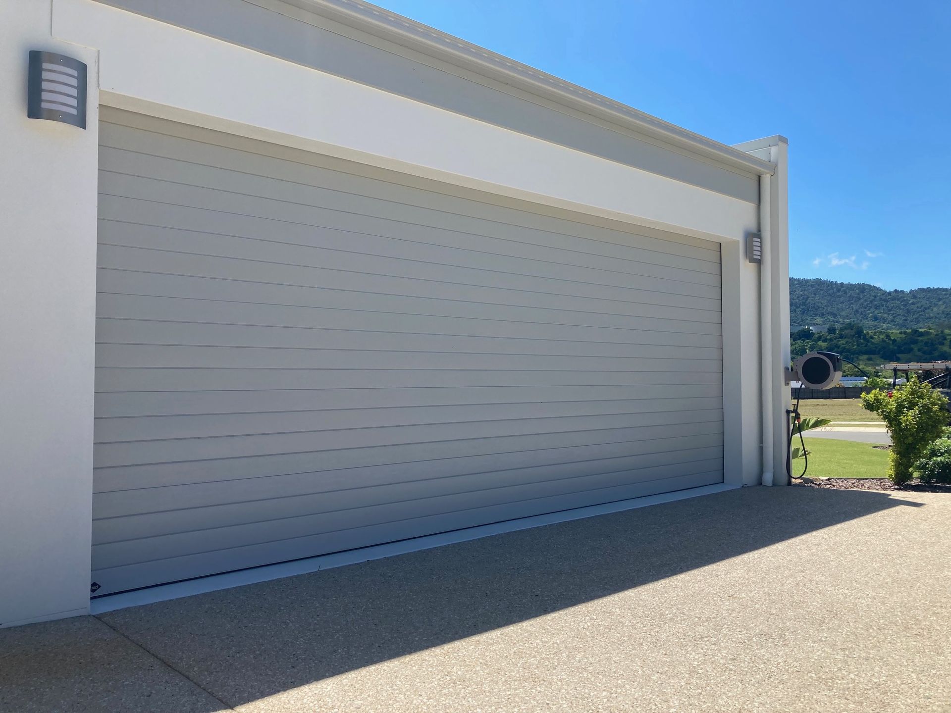 A Grey Garage Door with security light under blue skies— Airlie Beach Garage Doors In Cannonvale, QLD