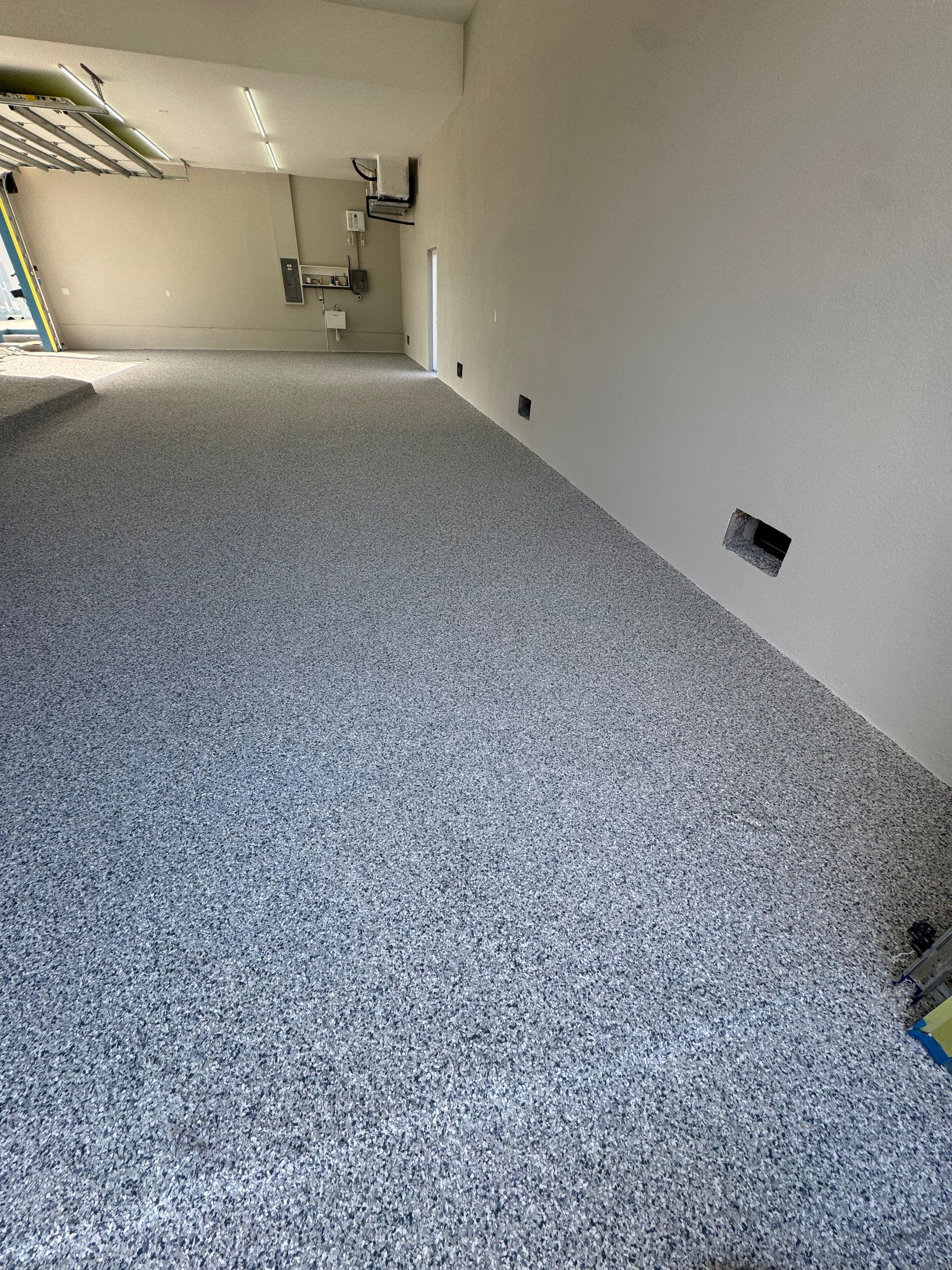 Empty carpeted room with white walls and exposed pipes along the ceiling