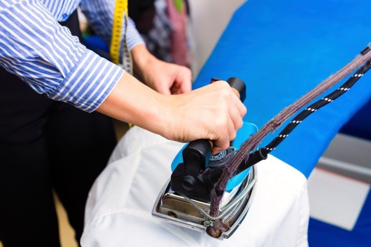 Una persona está planchando una camisa blanca en una tabla de planchar azul.