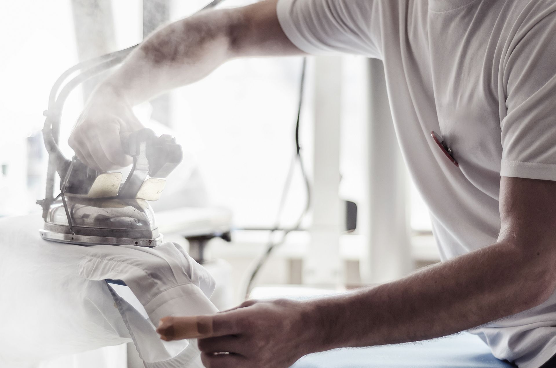 Un hombre está planchando una camisa con una plancha de vapor.