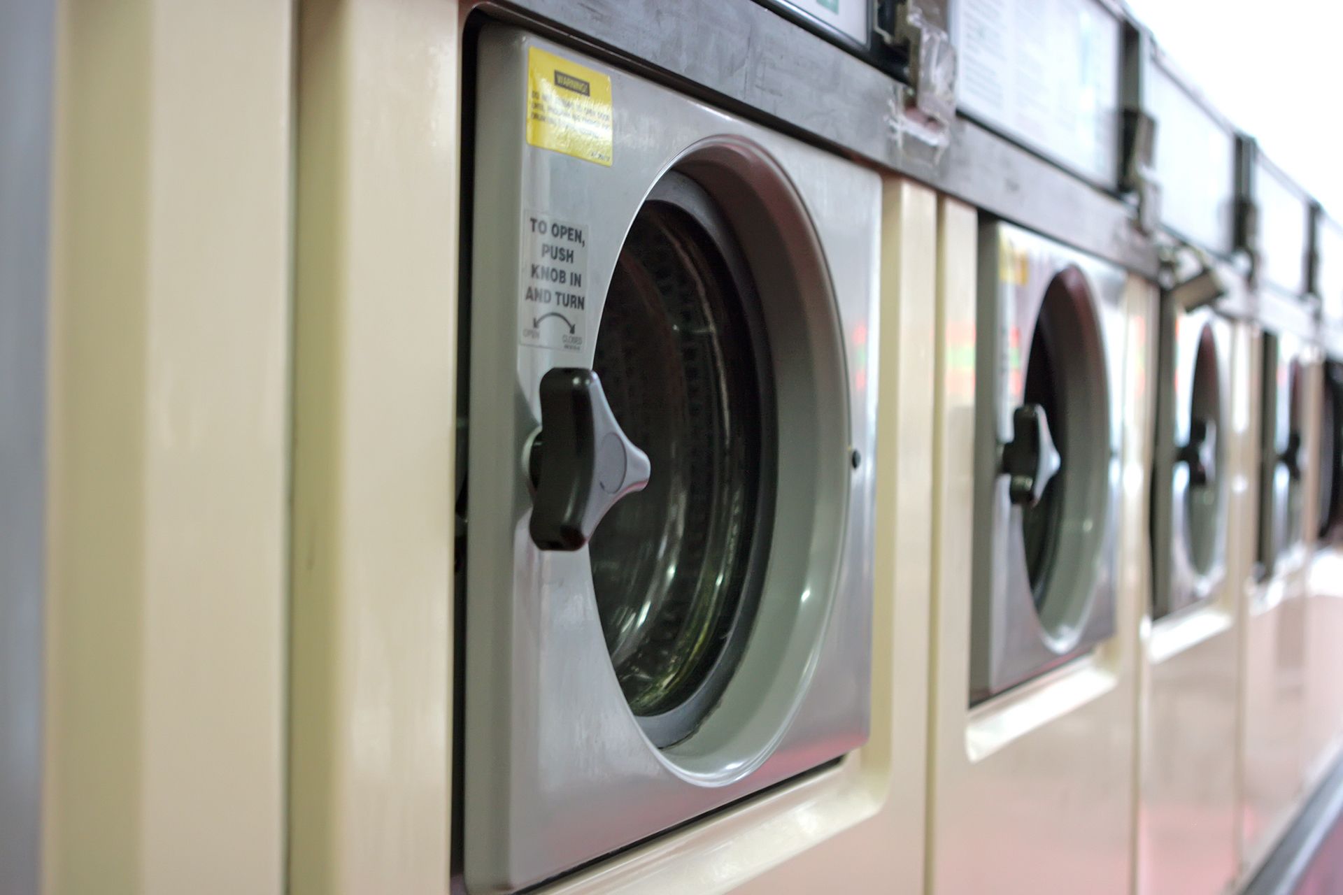 Una fila de lavadoras están alineadas en una lavandería automática.
