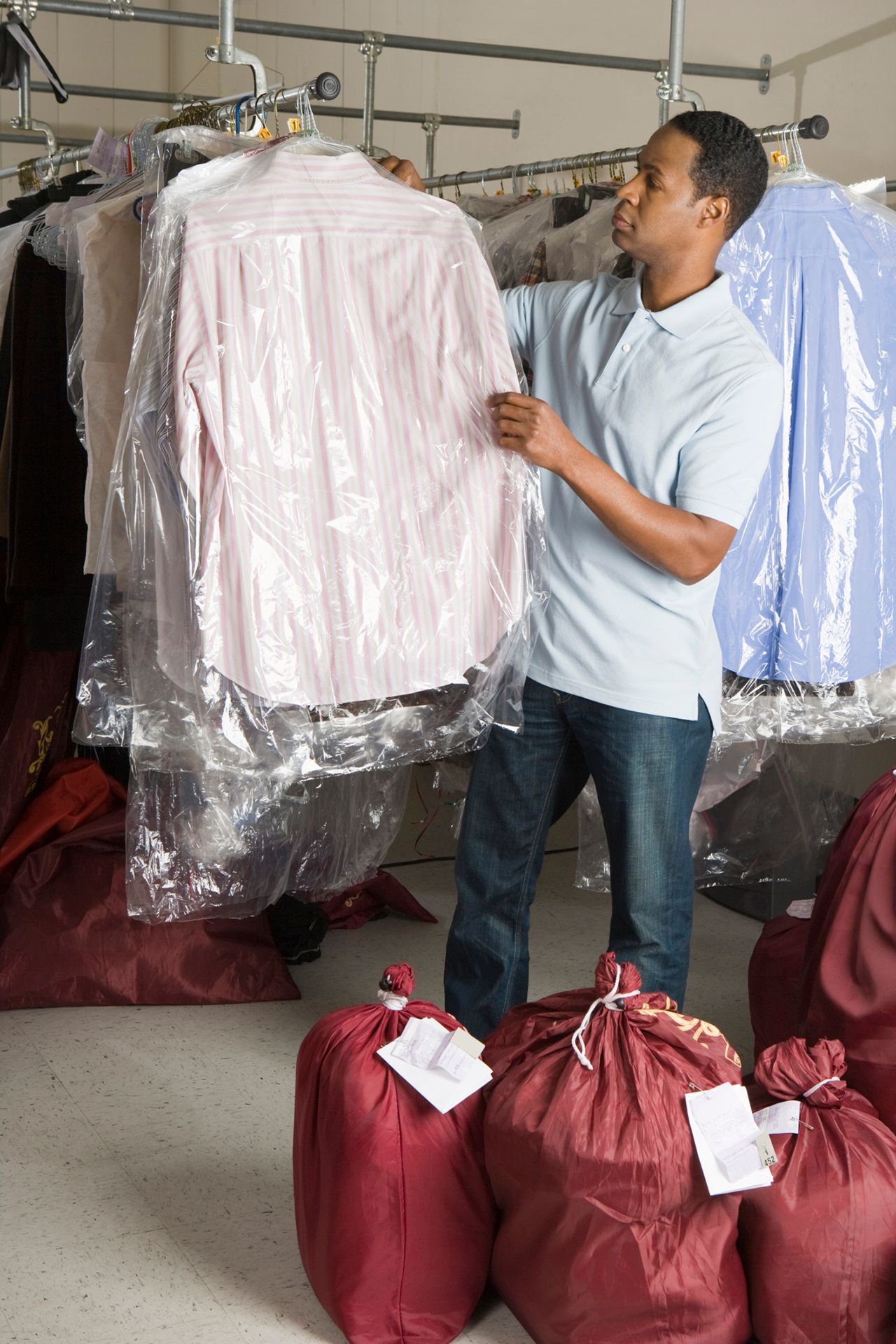 Un hombre sostiene una camisa rosa en una lavandería.