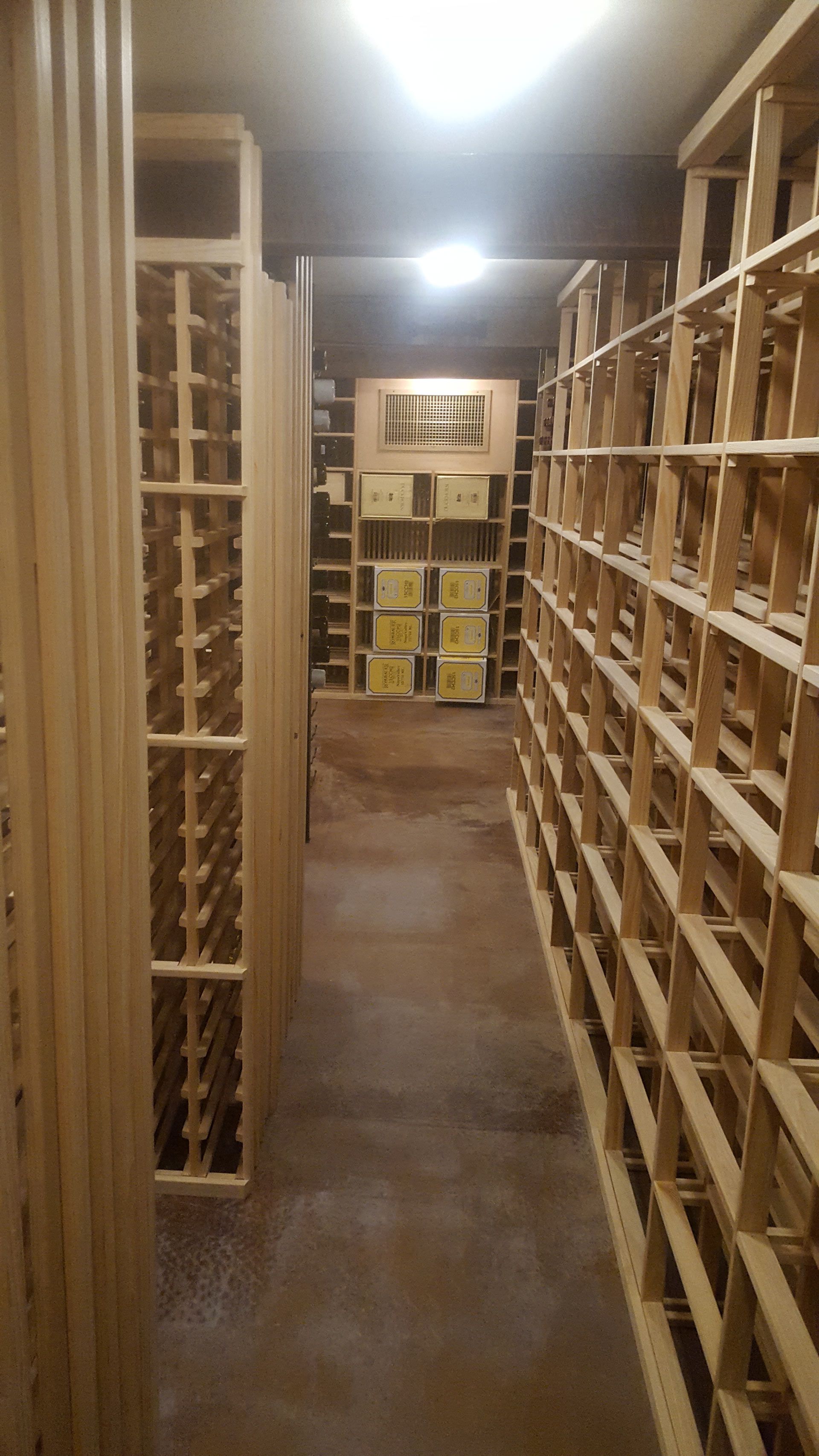 A row of wooden shelves filled with bottles of wine in a wine cellar — Pinellas County, FL —  R. J. Lange  & Son Inc.