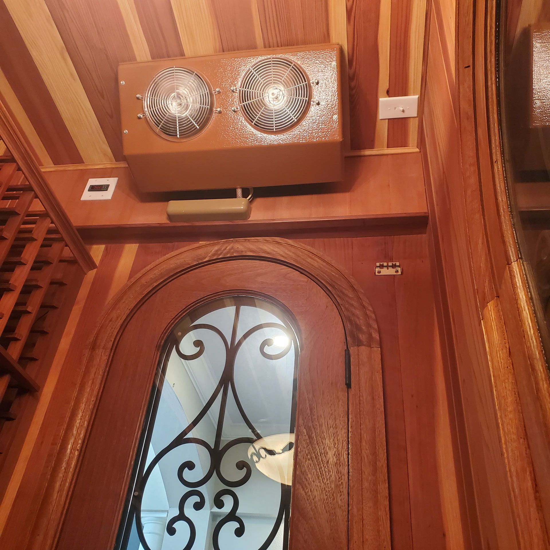 A wooden door with a wrought iron grille and a fan above it — Pinellas County, FL —  R. J. Lange  & Son Inc.