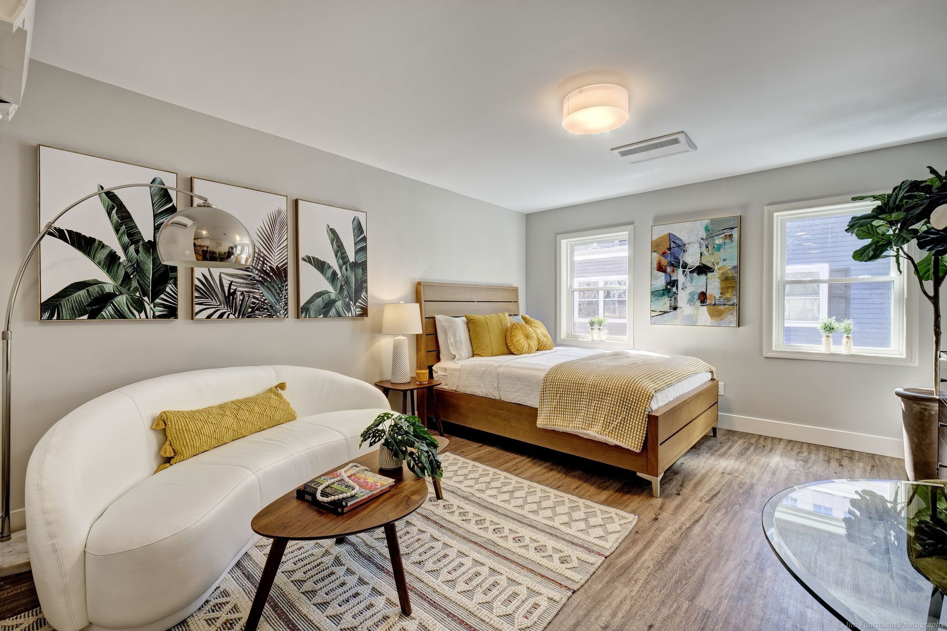 A bedroom with a bed , couch , coffee table and paintings on the wall.