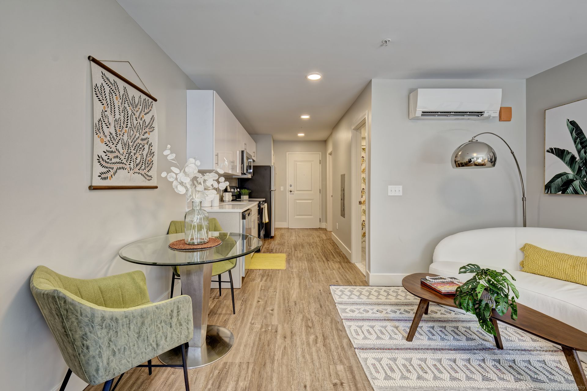 Cozy apartment interior with dining area, kitchen, and living space; features modern furniture, neutral walls, and natural light.