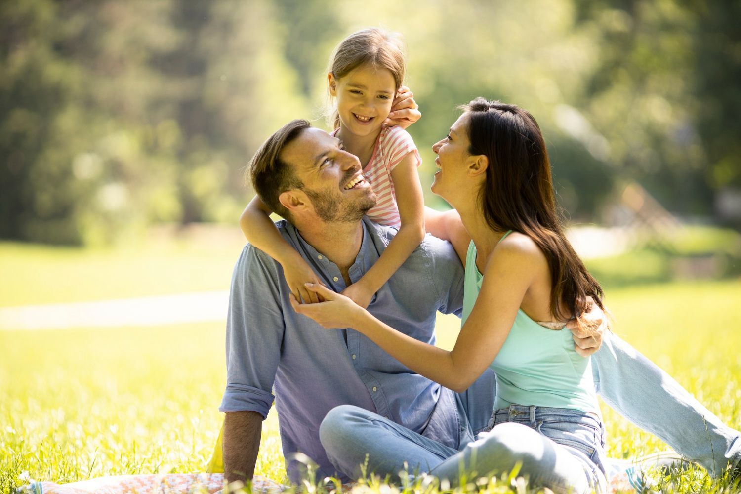 A family is sitting on the grass in a park.
