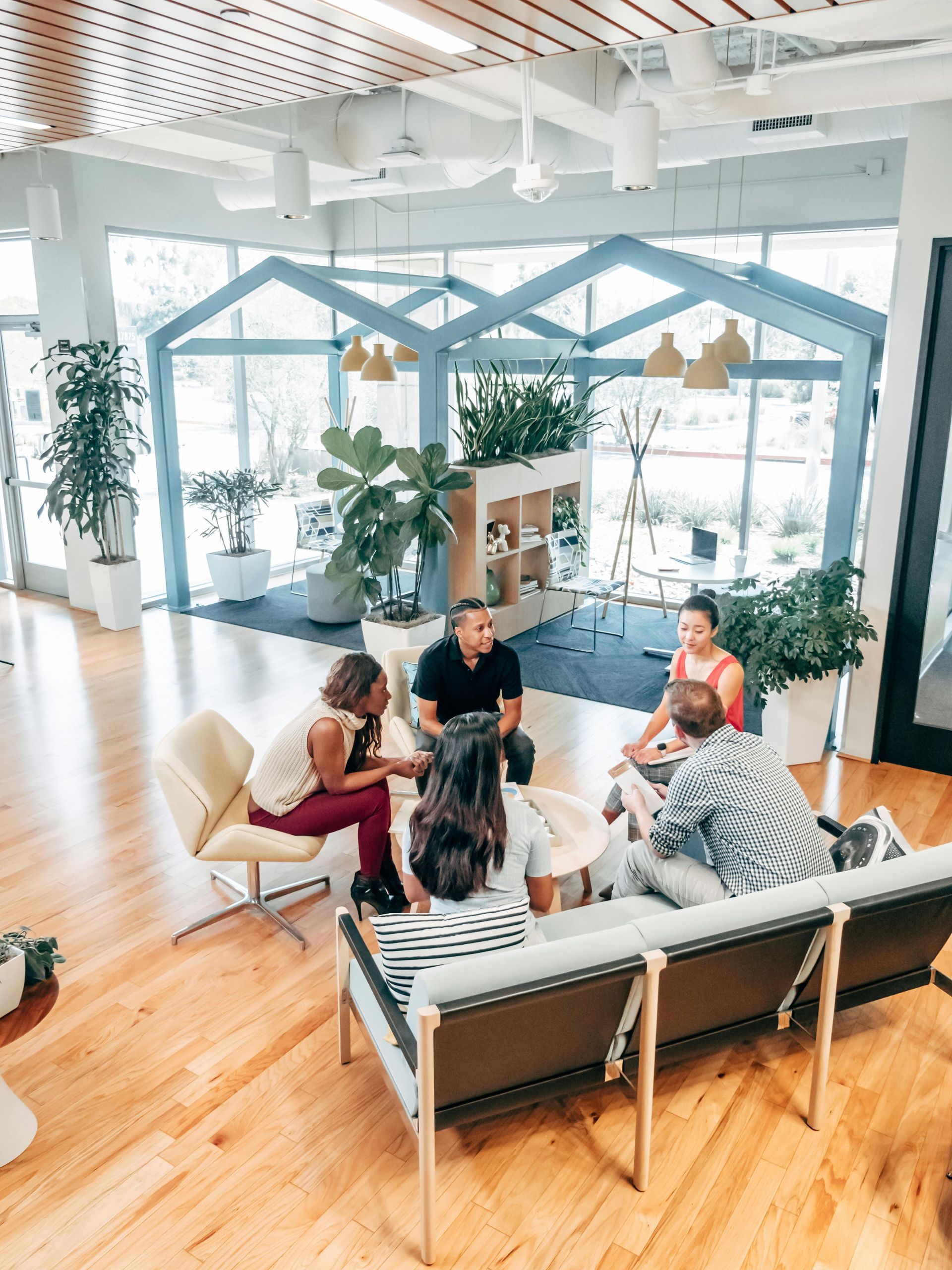 A group of people are sitting around a couch in a living room.