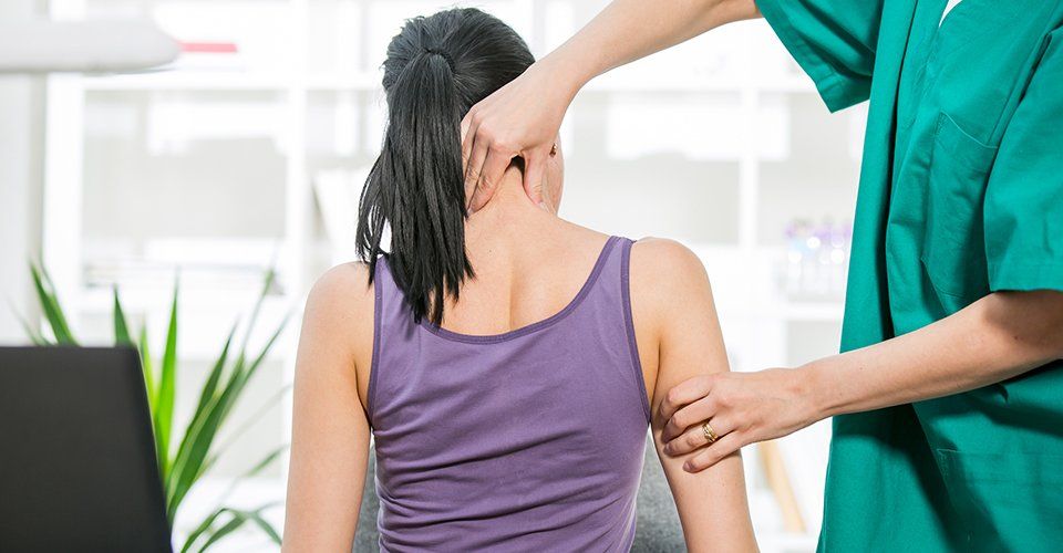 Examination — Doctor examining the neck of his patient while stretching it in Brea, CA