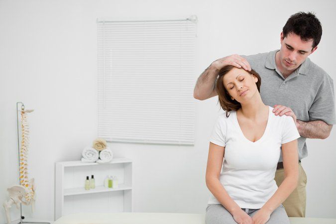Examination — Doctor examining the neck of his patient while stretching it in Brea, CA