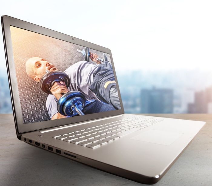 A laptop computer with a picture of a man following a online workout plan
