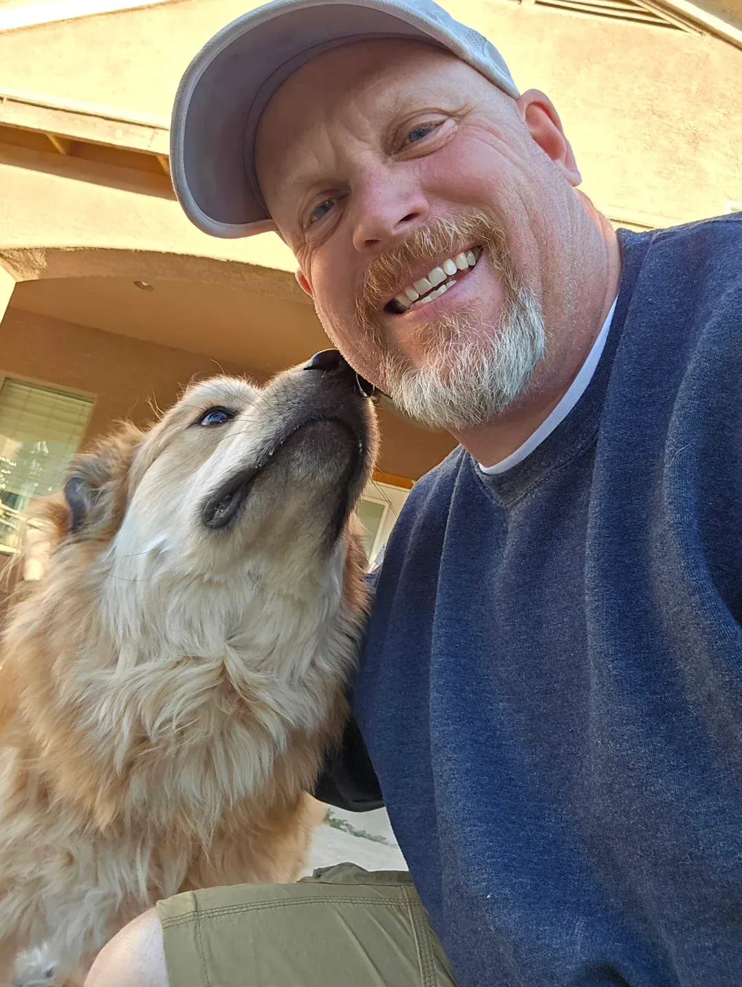 A man with a beard is smiling while holding a dog.