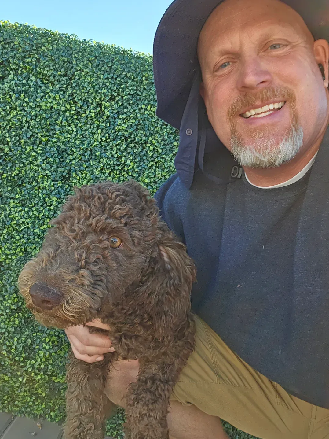 A man is holding a small brown dog in his arms.