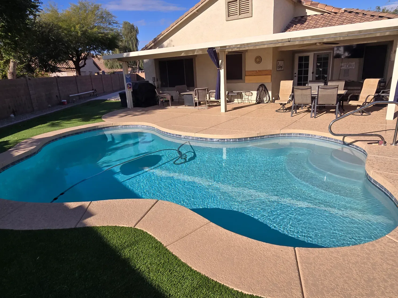A large swimming pool is in the backyard of a house.