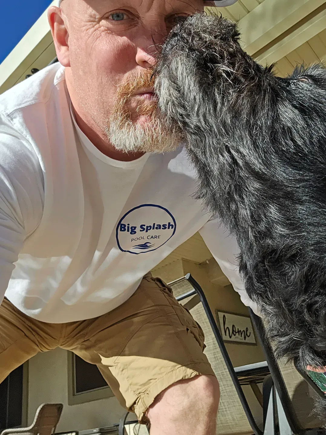 A man is kissing a small dog on the nose.