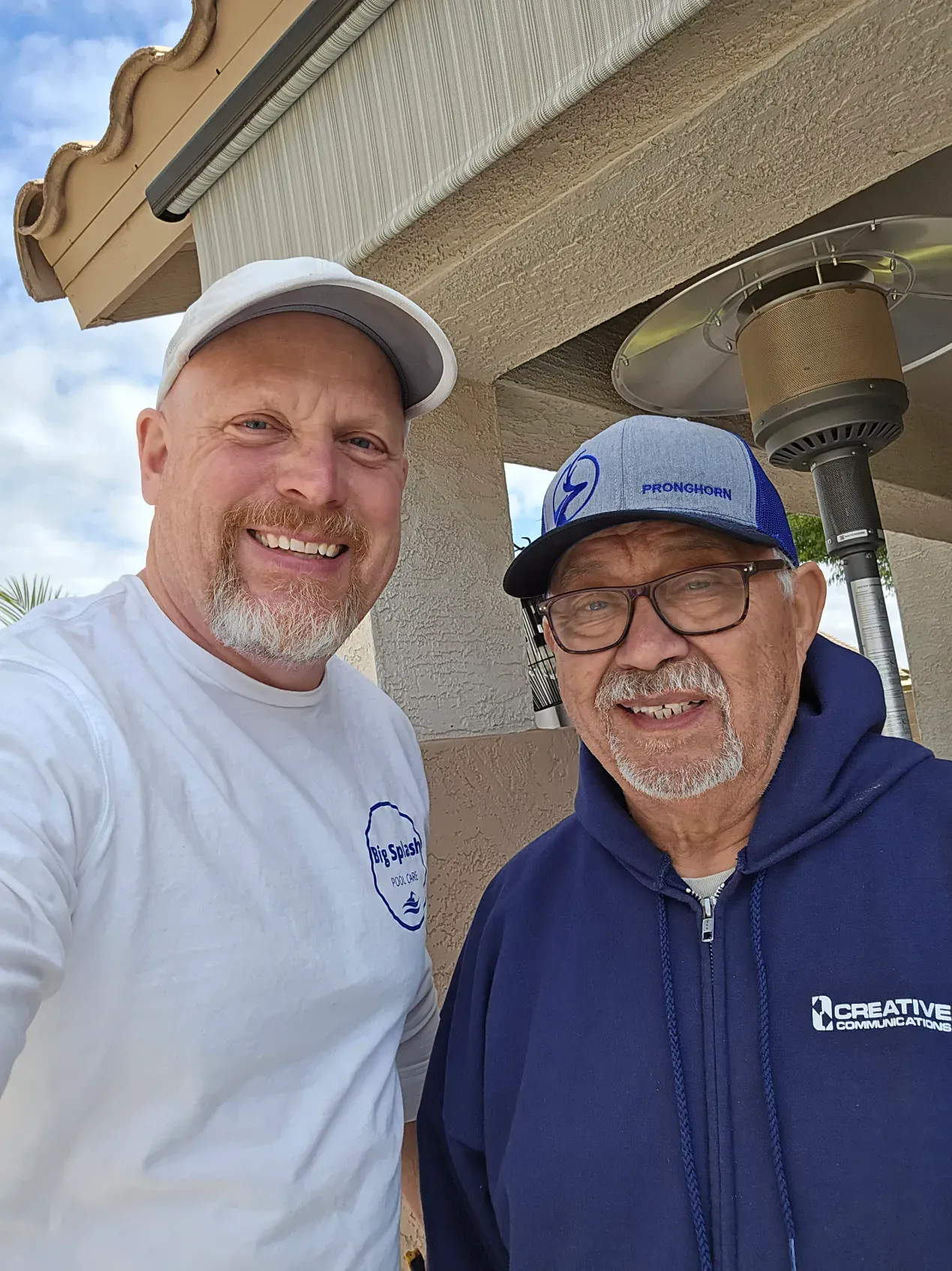 Two men are standing next to each other and smiling for a picture.