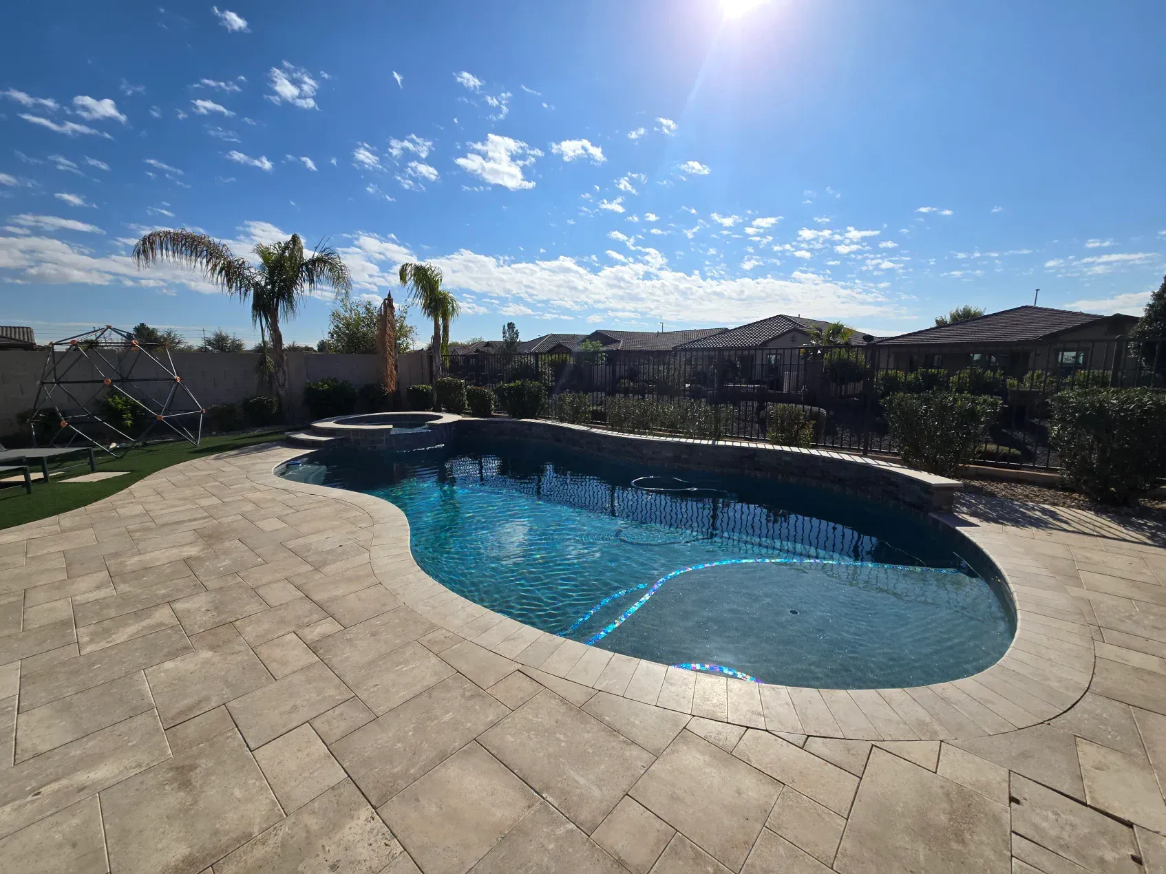 There is a large swimming pool in the backyard of a house.