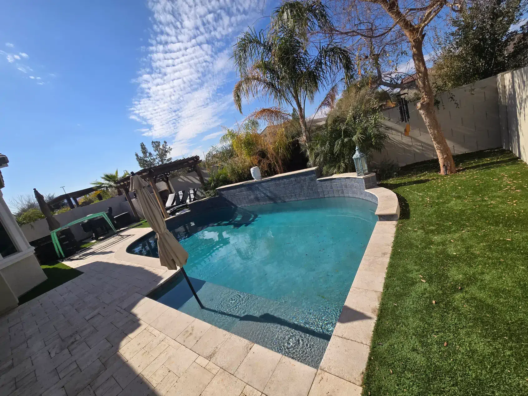There is a large swimming pool in the backyard of a house.