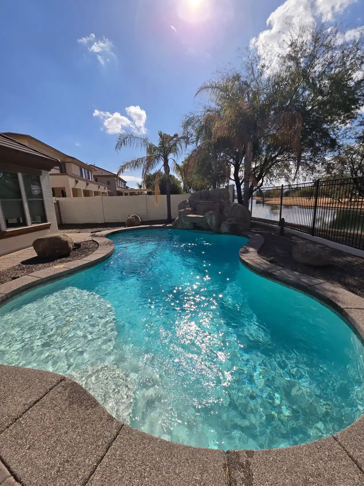 There is a large swimming pool in the backyard of a house.