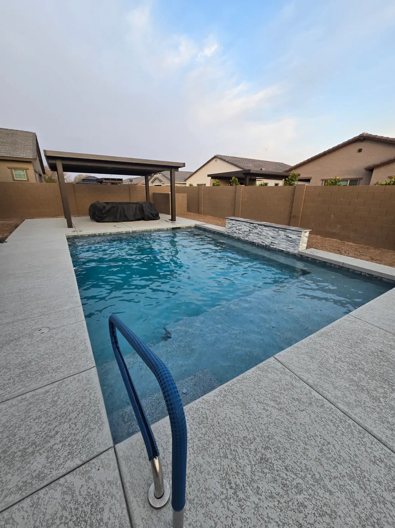 There is a large swimming pool in the backyard of a house.