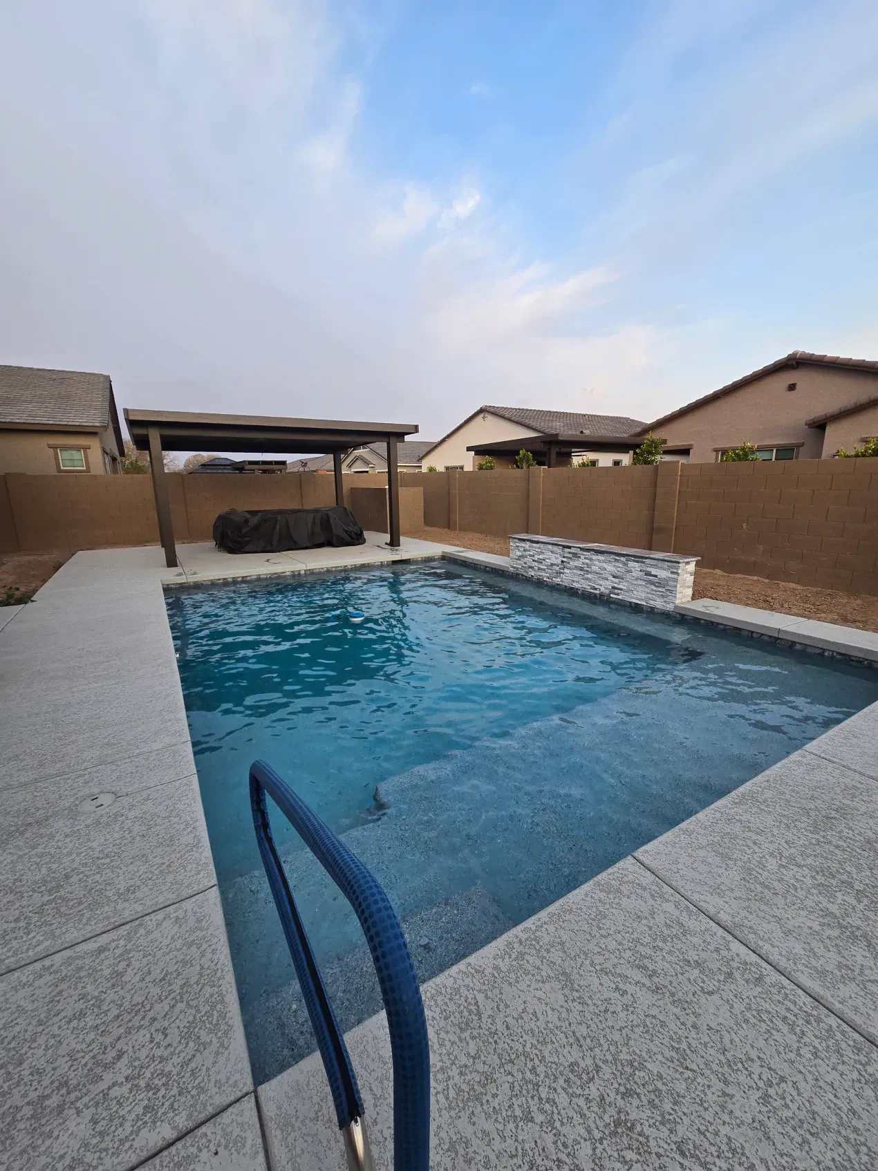There is a large swimming pool in the backyard of a house.