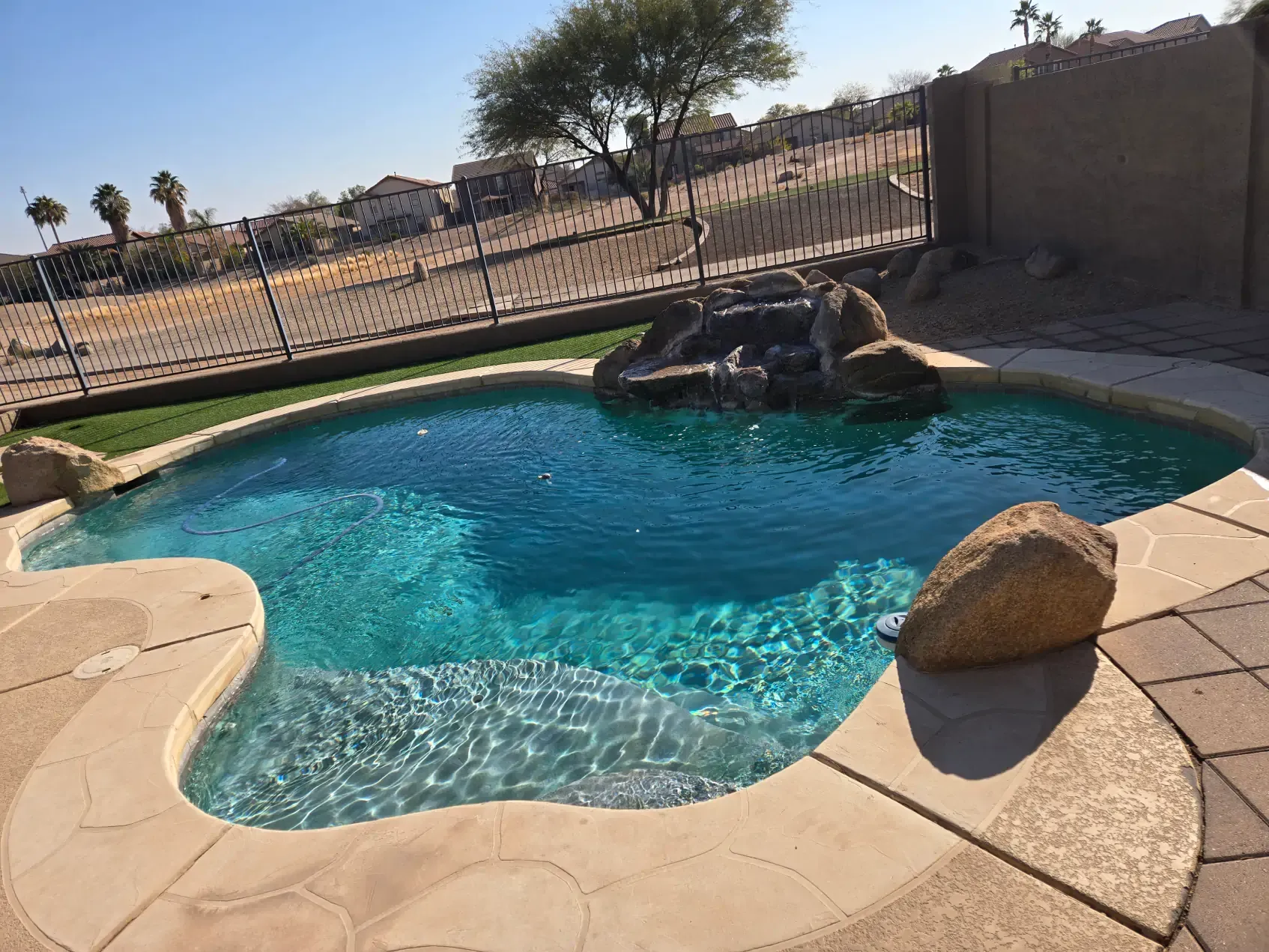 A large swimming pool with a waterfall in the middle