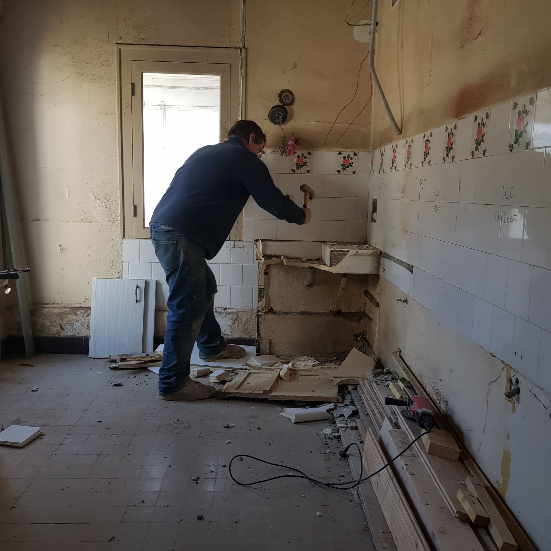 man renovating a kitchen using a hammer