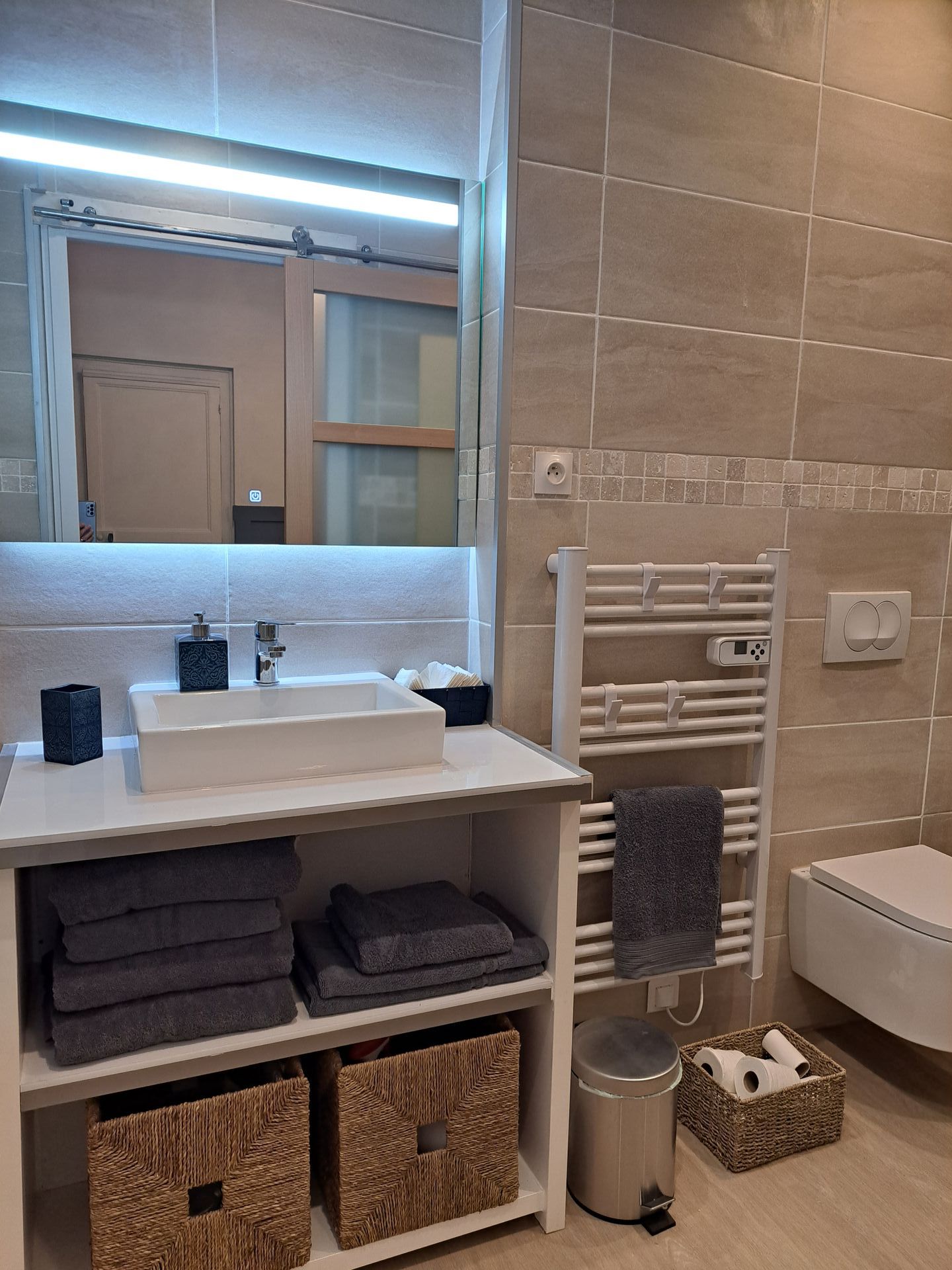 large bathroom mirror over a white sink and a white heated towel rail to the side